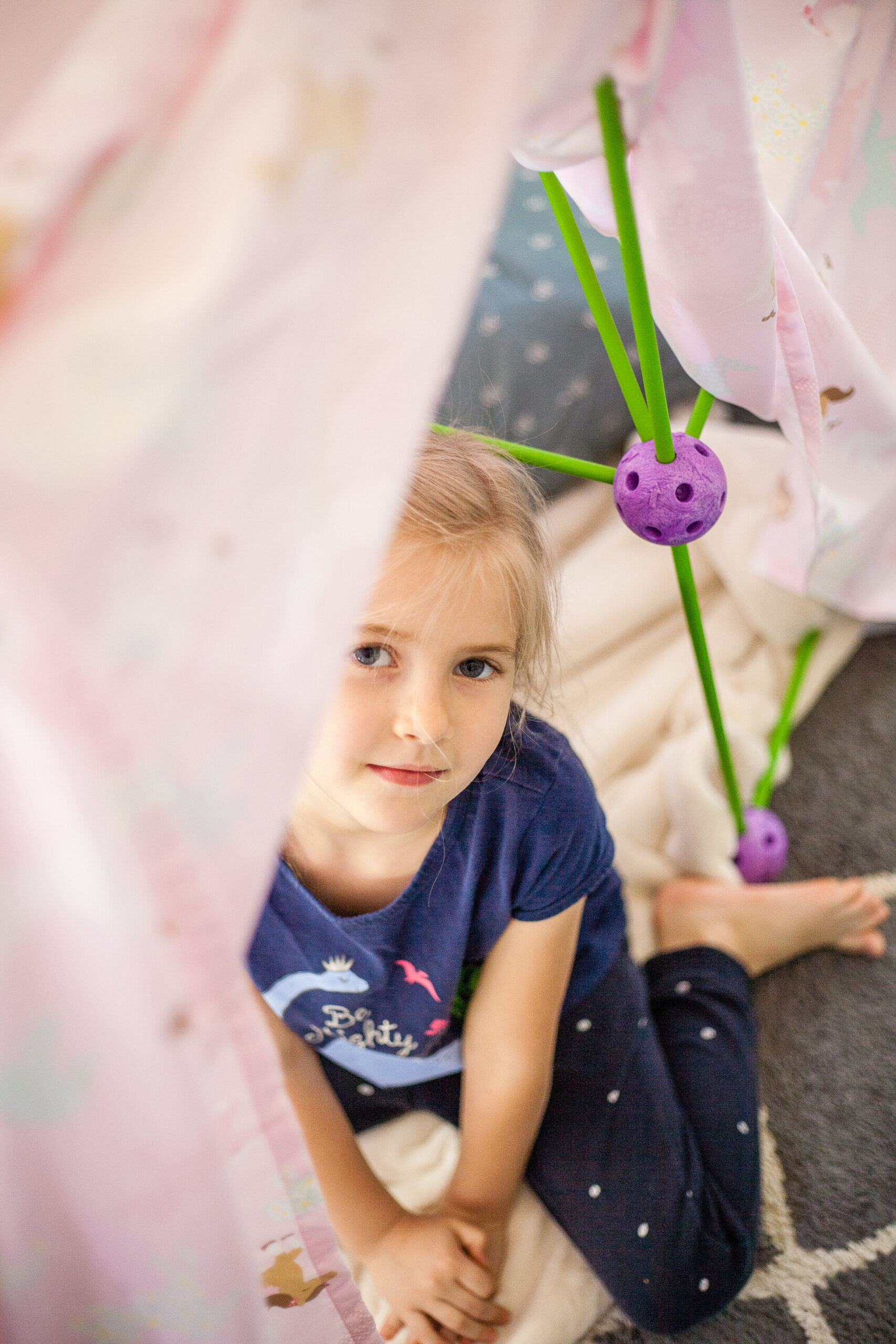 At home kid activities: girl in a blanket fort