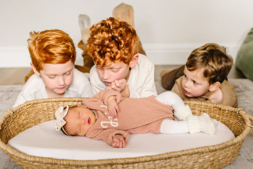 Older brothers watch over baby sister at an in-home newborn photo session in Fresno, CA. 